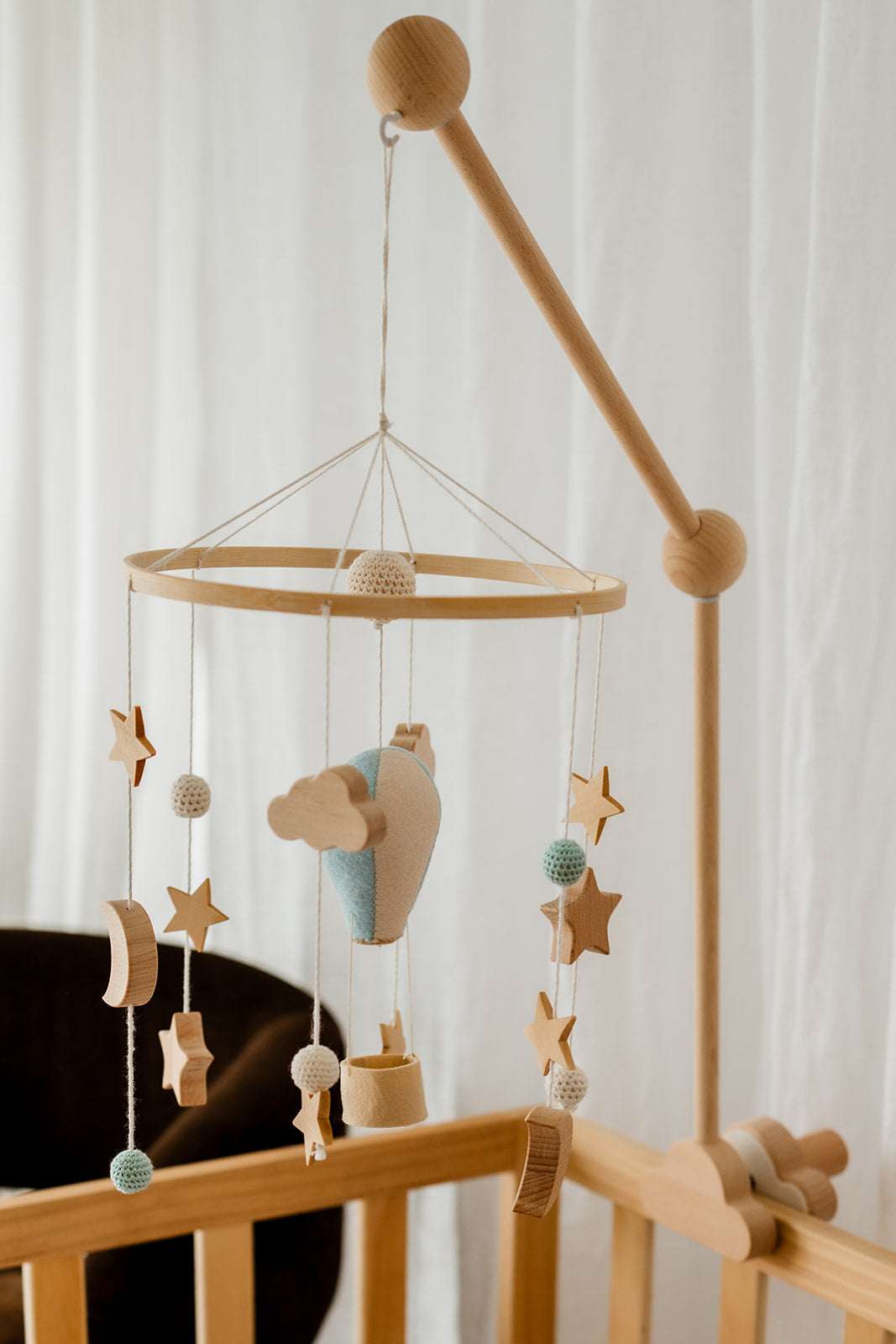 Blue balloon baby mobile hanging above crib in neutral nursery